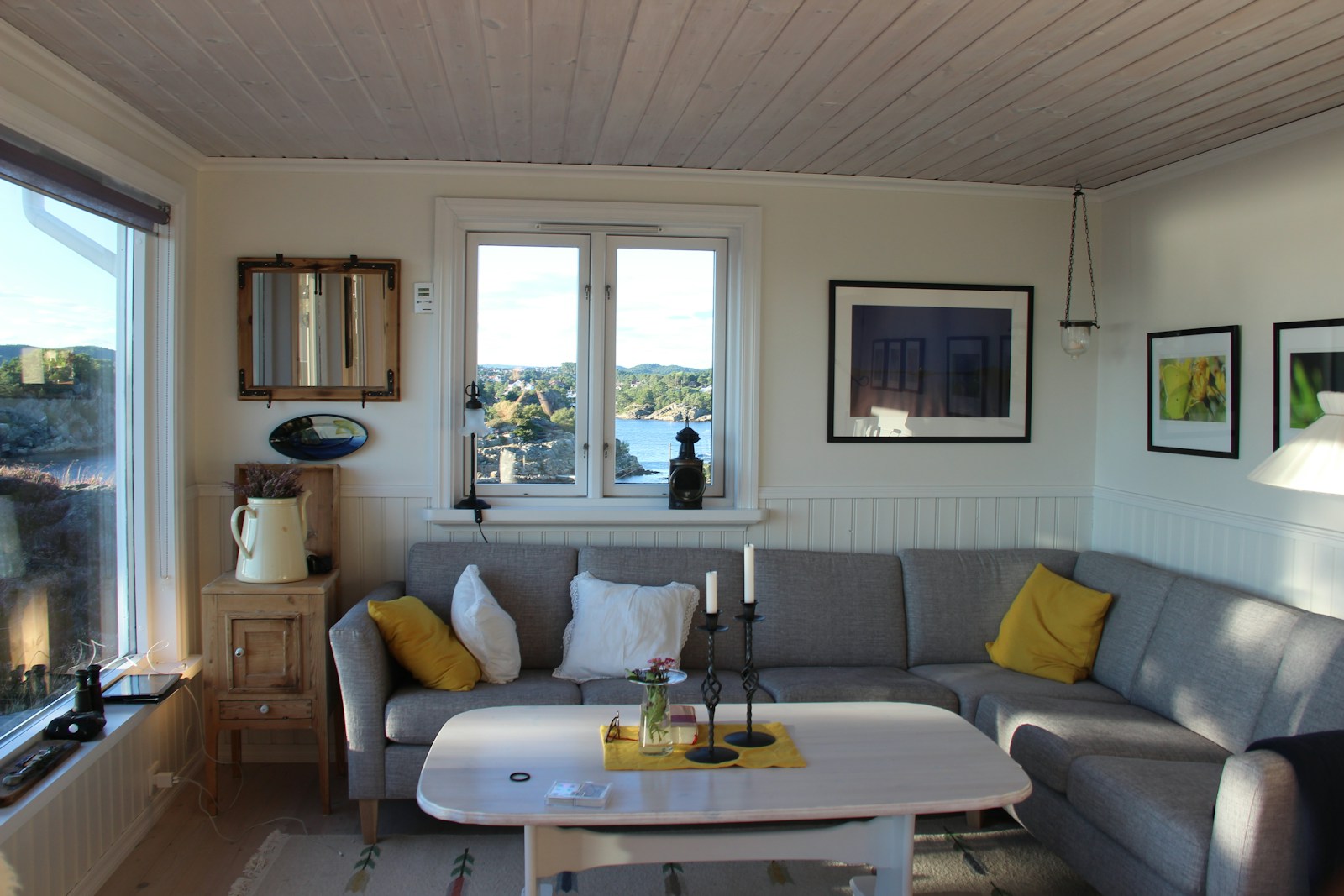 A comfortable living room with a gray sofa, yellow cushions and natural light